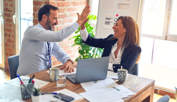 Two corporate employees at a table giving a high-five